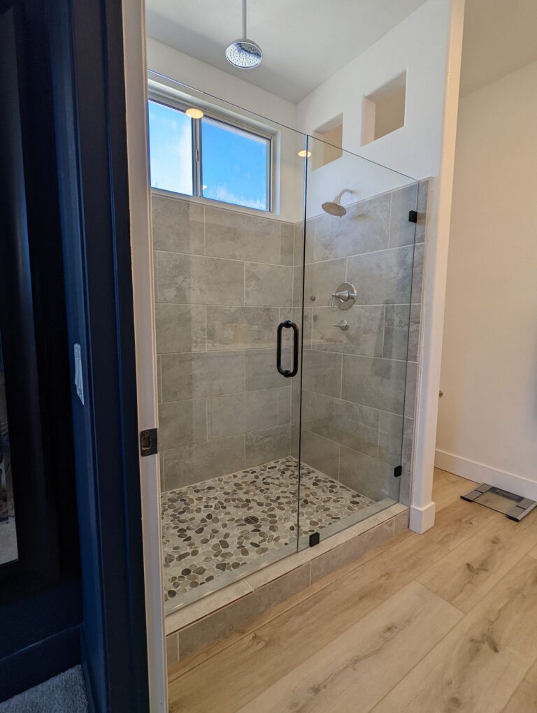 frameless-walk-in-glass-shower-installation Walk-in frameless glass shower with rain showerhead and custom tile work installed by Westoaks Glass & Mirror.
